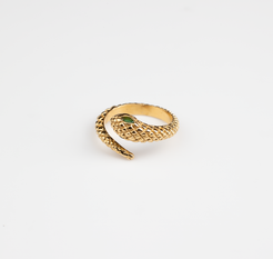 This ring features a snake motif, coiling around the finger with the opening positioned at the head where the snake's head meets its tail. The snake's head is adorned with a vibrant green gemstone, serving as its eyes. Lifelike scales cover the entire surface of the ring, available in both gold and silver options.