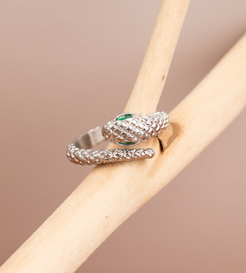 This ring features a snake motif, coiling around the finger with the opening positioned at the head where the snake's head meets its tail. The snake's head is adorned with a vibrant green gemstone, serving as its eyes. Lifelike scales cover the entire surface of the ring, available in both gold and silver options.