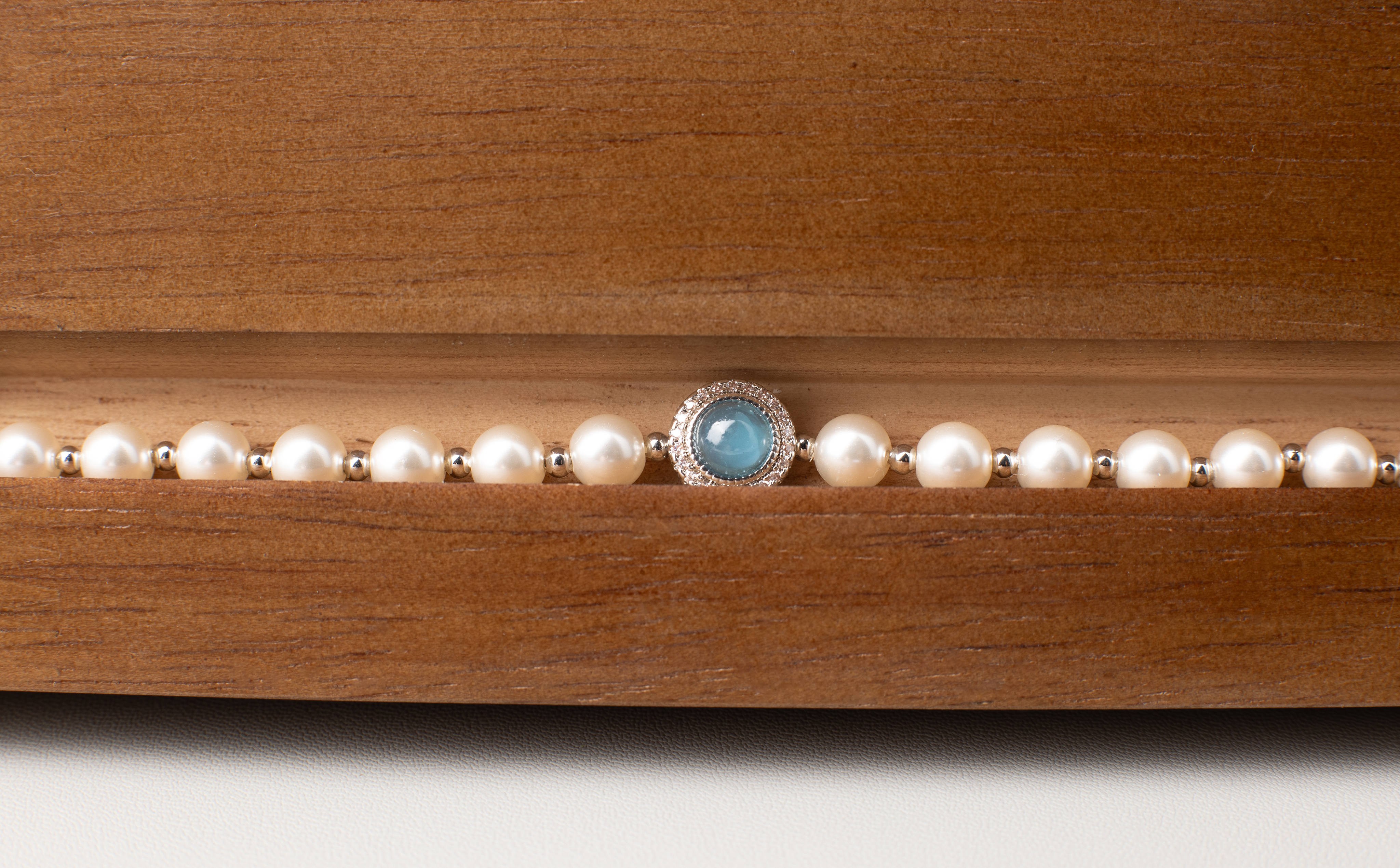 Adjustable in size, our bracelet offers both white and silver pearl options adorned with blue gemstones, exuding elegance and sophistication. Suitable for formal occasions and everyday wear, this women's bracelet makes an elegant gift choice.