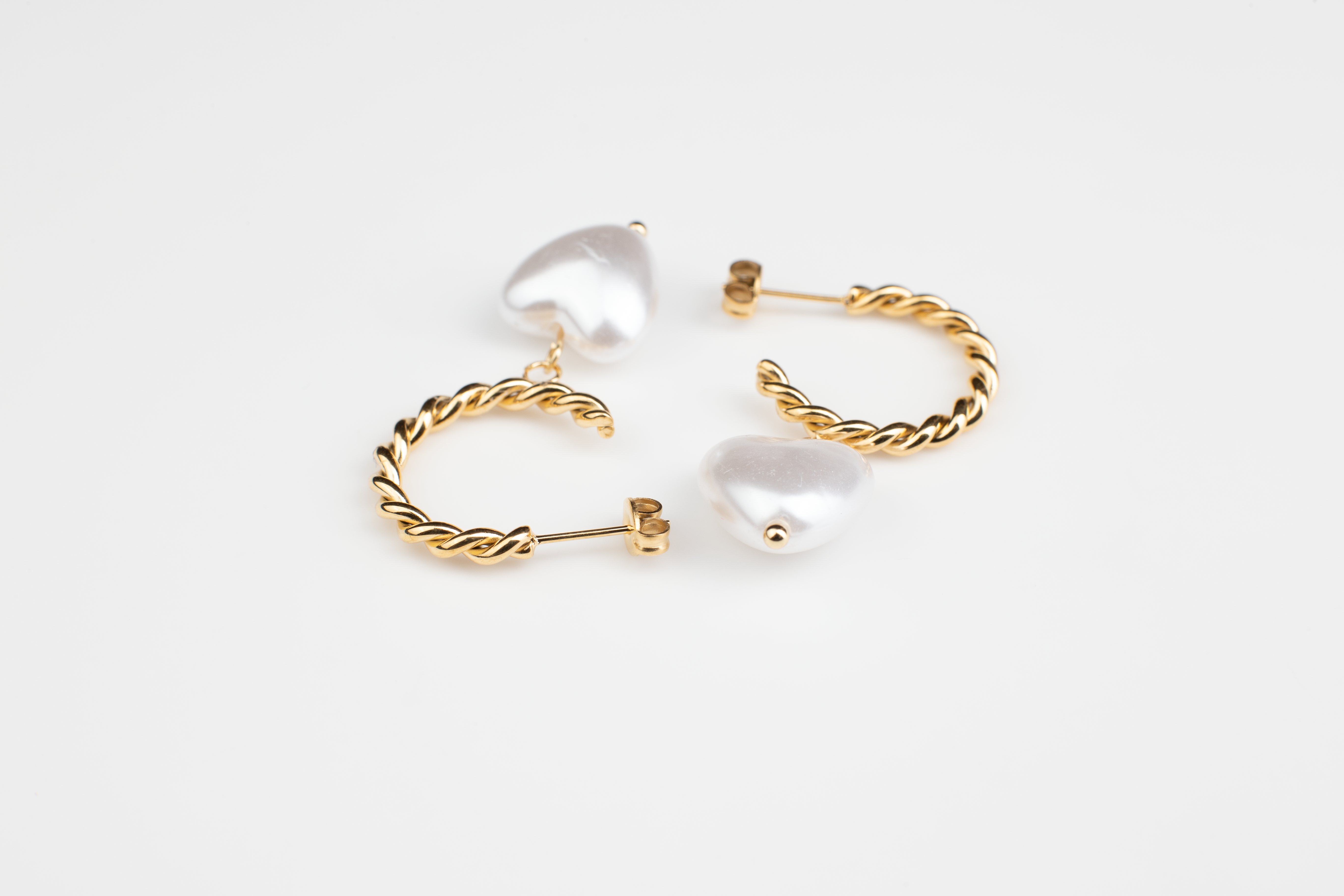 Enhance your elegance with these chic gold earrings adorned with white heart-shaped pearls, perfect for women of all occasions. Crafted from titanium steel plated with 18K gold, they're versatile for formal affairs or leisurely outings. An ideal gift selection for someone special.