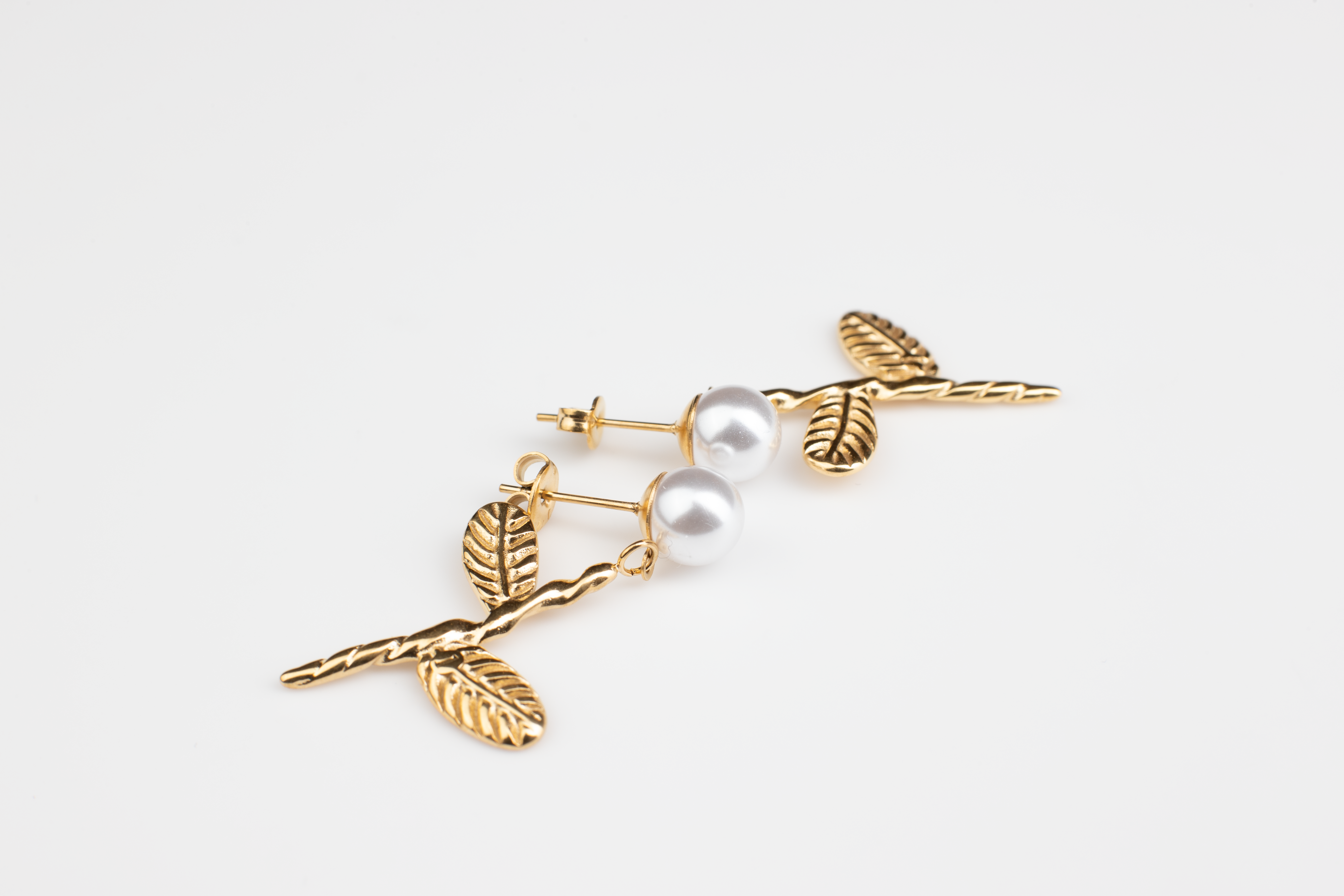 Adorn your ears with these charming dangles featuring lively pearl floral blooms and lifelike leaves. Crafted in titanium steel with 18K gold plating, these adorable and finely crafted earrings are perfect for casual occasions and make a versatile and delightful gift