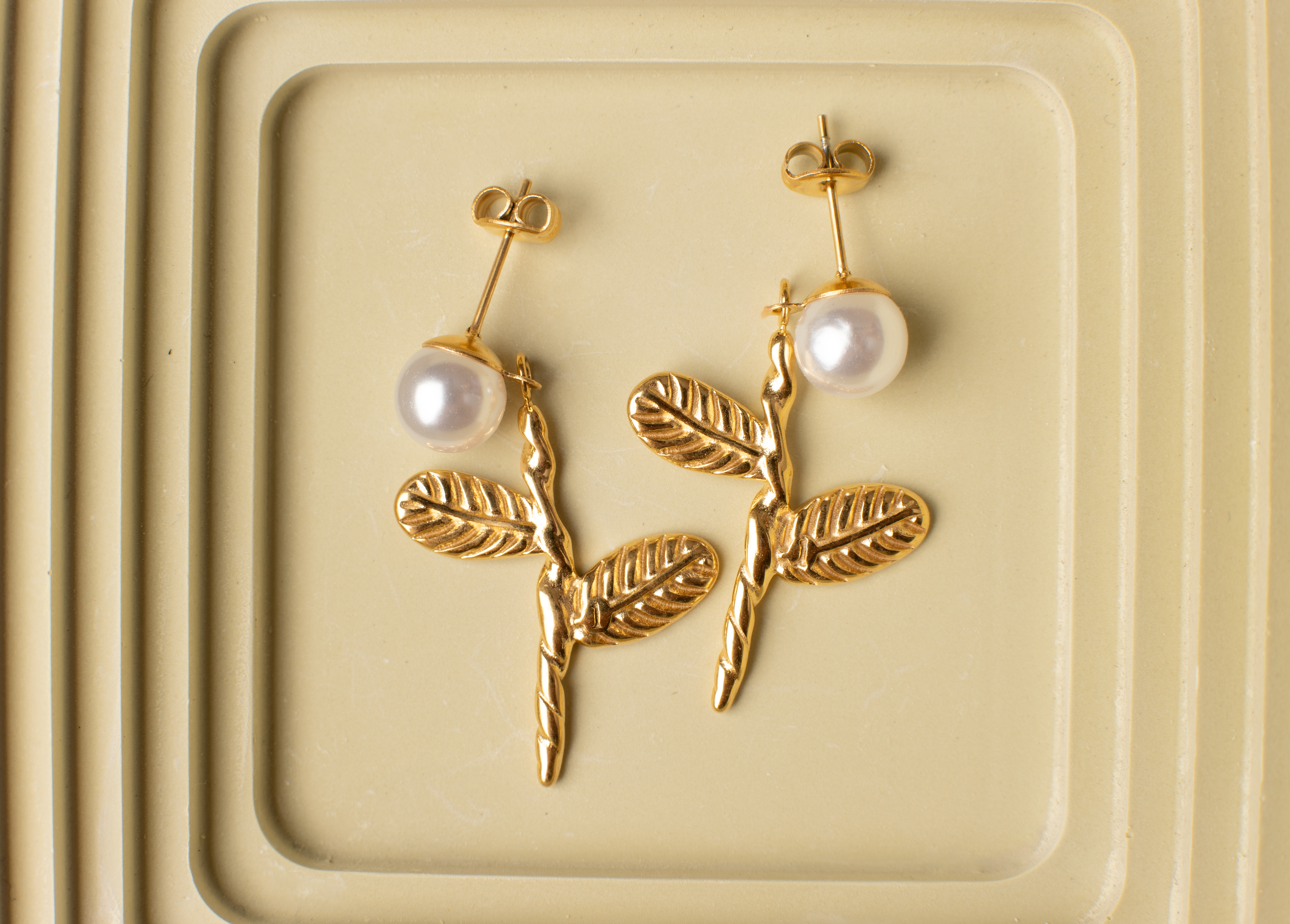 Adorn your ears with these charming dangles featuring lively pearl floral blooms and lifelike leaves. Crafted in titanium steel with 18K gold plating, these adorable and finely crafted earrings are perfect for casual occasions and make a versatile and delightful gift