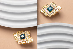 These diamond-shaped earrings feature a striking blue gemstone set within a golden frame adorned with sparkling diamond accents. Radiating luxury and elegance, they make a perfect accessory for women, suitable for various outfits and occasions. An ideal gift choice.