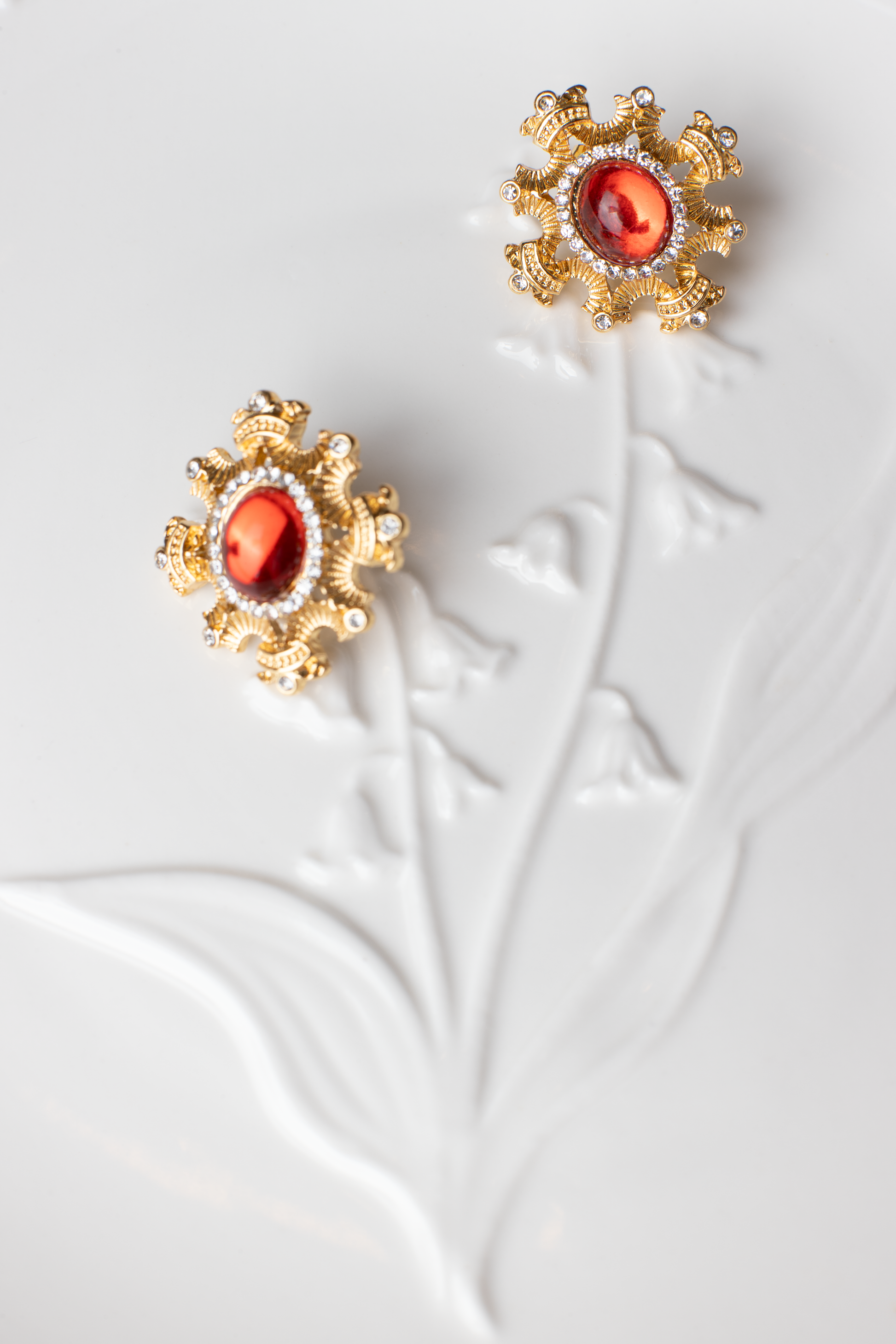 Adorn yourself with the regal elegance of red gemstone earrings encased in a blossoming gold frame. This bold and fiery design is suitable for various occasions, with the option of ear clips for added versatility. A perfect gift choice."