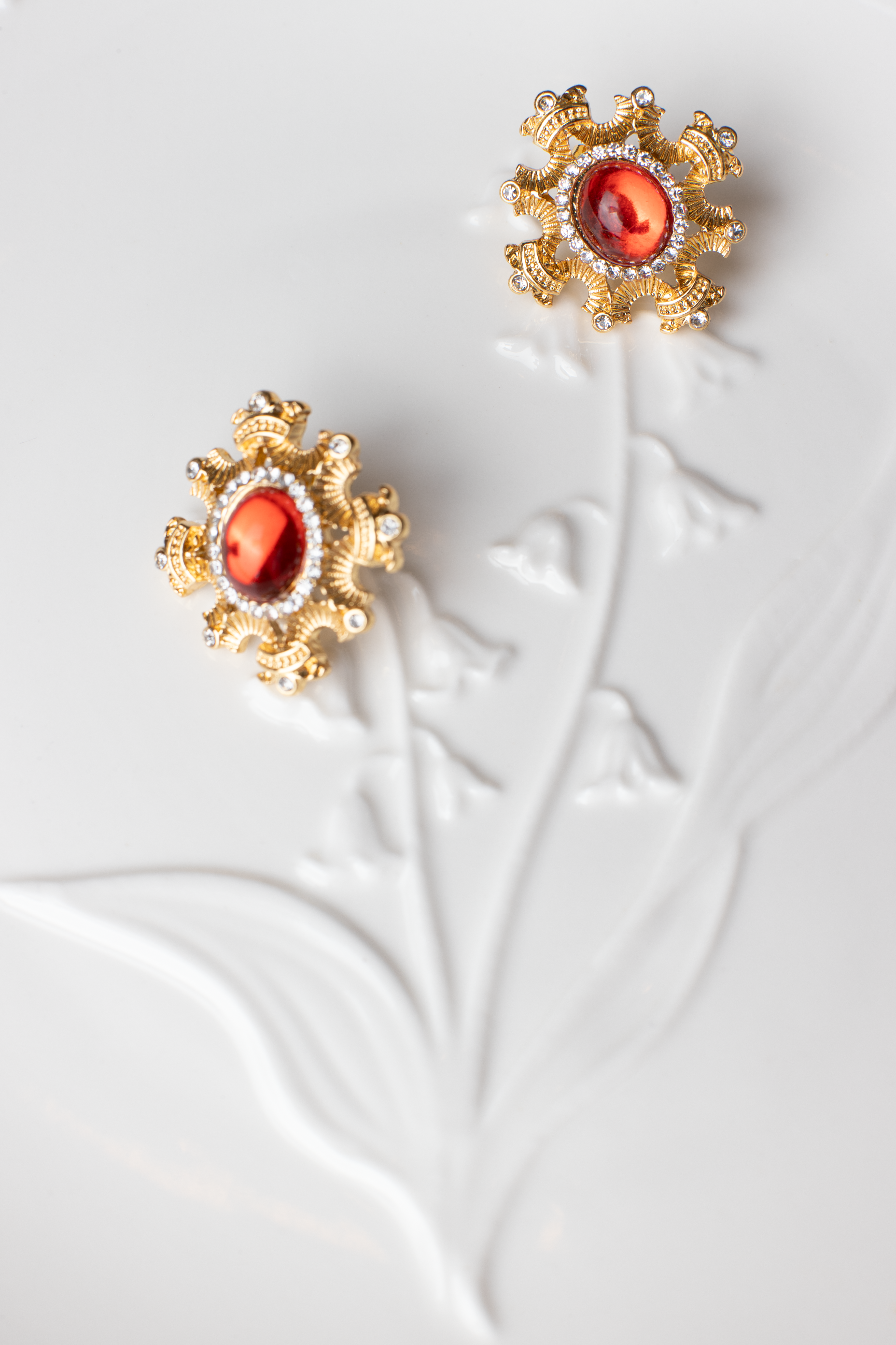 Adorn yourself with the regal elegance of red gemstone earrings encased in a blossoming gold frame. This bold and fiery design is suitable for various occasions, with the option of ear clips for added versatility. A perfect gift choice."