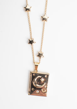 Book-shaped locket necklace with a celestial design featuring stars, a crescent moon, and sparkling gemstone accents. Crafted from copper with 14K gold plating, this locket opens from the side to reveal a hidden photo compartment, elegantly displayed against a clean white background.