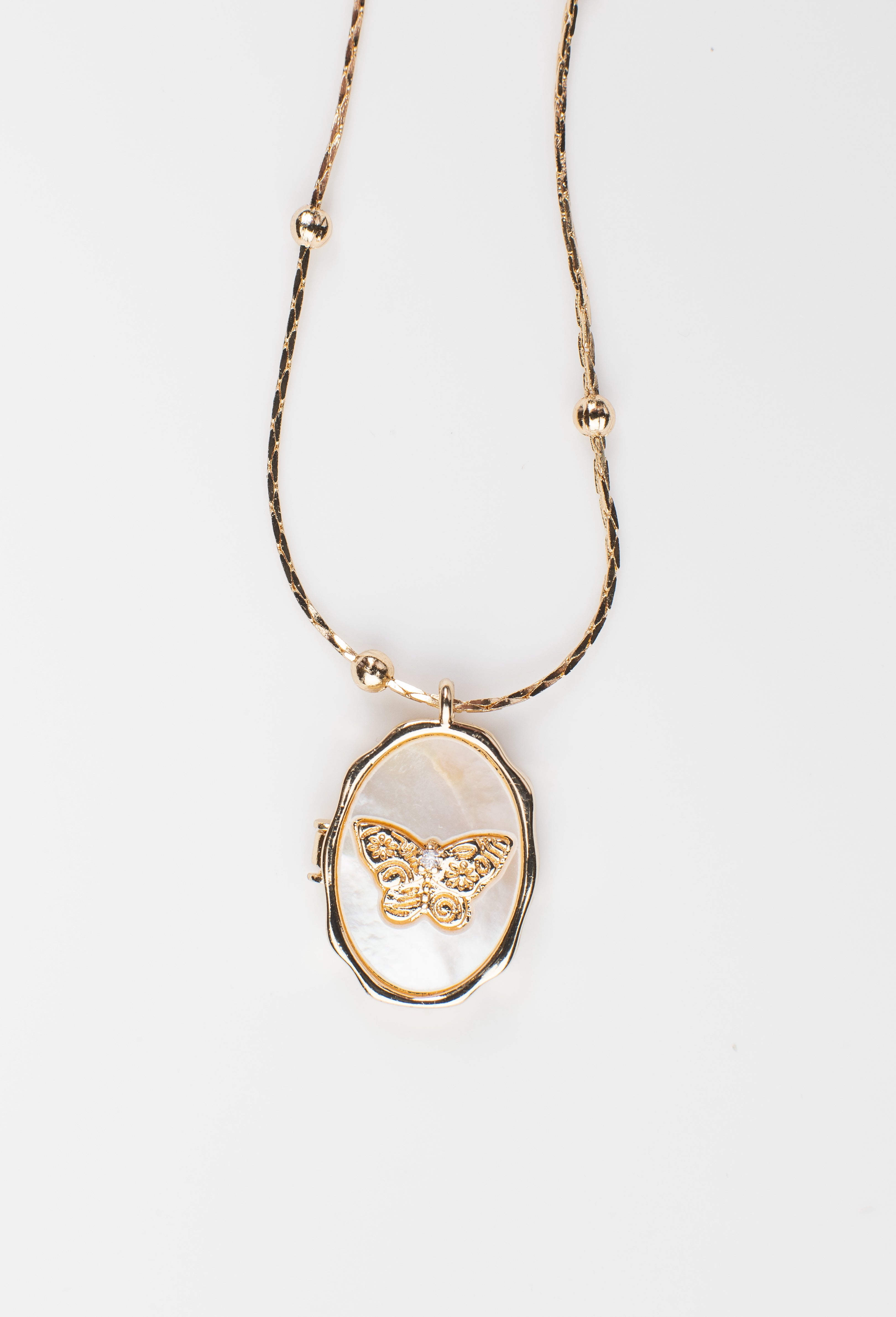 Oval locket necklace featuring a delicate butterfly design over a mother-of-pearl background, crafted from copper with 14K gold plating. The locket opens to reveal a hidden compartment, perfect for holding a cherished photo. Displayed on a clean white background to emphasize its elegant craftsmanship.